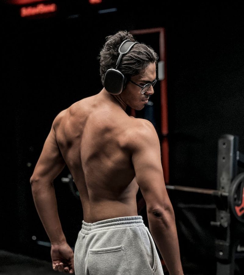 Athletic man performing a strength exercise in a modern, dark gym.