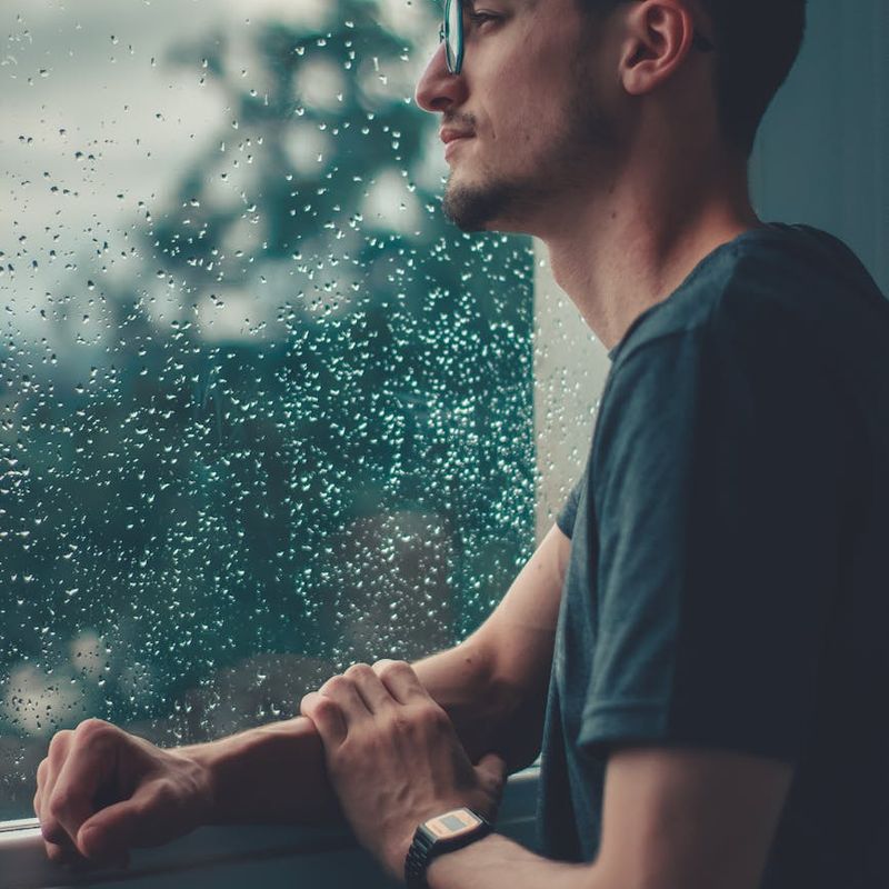 Man in a state of calm focus after a workout, looking out a large window.